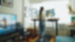 A woman walking on a treadmill desk while working on multiple monitors in a bright home office