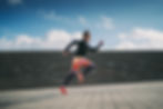 Runner sprinting up outdoor steps in vibrant athletic gear.