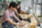 People enjoying a pottery class, shaping clay on pottery wheels in a studio.