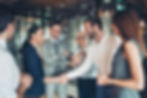 Two professionals shaking hands in an office environment, celebrating a successful agreement.