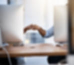 Two coworkers at adjacent desks fist-bumping over computer screens, celebrating teamwork and collaboration in the workplace.