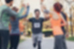A man running to the finish line during a race, and people waiting to high-five him