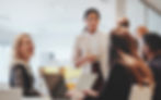 Woman leading a meeting, smiling with colleagues in an office.
