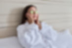 Woman relaxing with a white robe in a spa, with cucumber as eye patches.