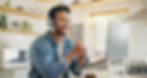 Man wearing headphones, smiling during an online video call from a cozy home office.
