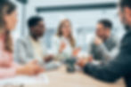 Diverse group of professionals in a meeting, one woman speaking