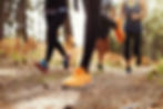 Close-up of runners' feet on a trail in a forest, focusing on their colorful sneakers.