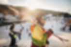 A person walking with skis on their shoulder, with full ski apparel, in a snowy mountain