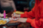 A person in a red sweater marking a bingo card with a red pen during a game.