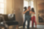 A father joyfully hugging his two children at the doorway of their home.
